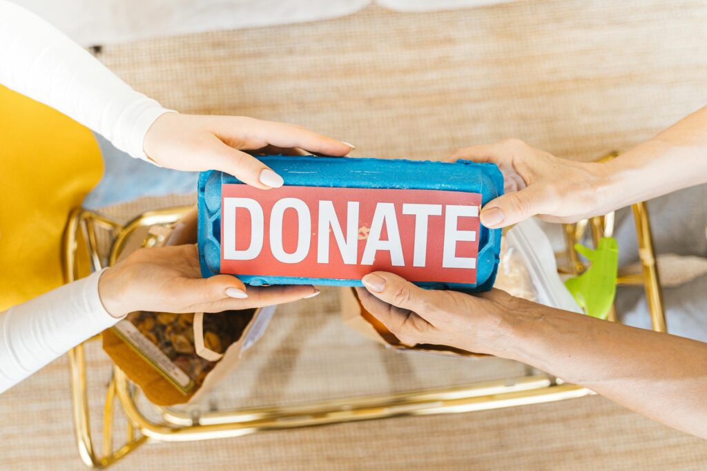 Hands exchanging a donation box filled with items, symbolizing giving and community support.